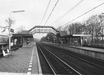 150440 Gezicht op perrons, voetgangersbrug en sporen van het N.S.-station Hilversum N.O.S. te Hilversum.De naam ...